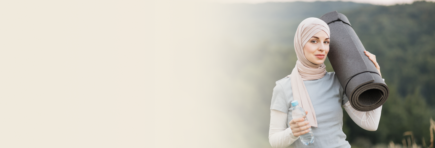 A woman wearing a hijab holding a yoga mat.