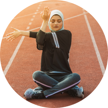 A woman sitting on a running track and stretching  her hands